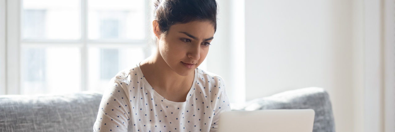 Learning How to Cope With Anxiety as a Successful Teen Woman in STEM young woman working on her computer, hair up in a bun with a white blouse that has black dots on it
