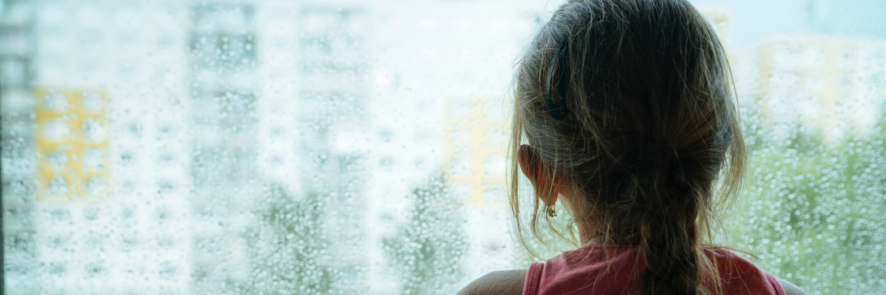 What It's Like to Be a Child With Undiagnosed Disabilities a young girl looking out a window