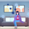 An illustration of a woman sitting on her couch holding a cup of tea. Visuals representing the coronavirus float around her