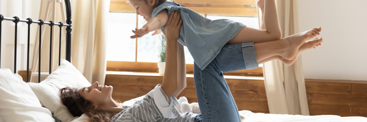 A young mom lifting her daughter up on her legs