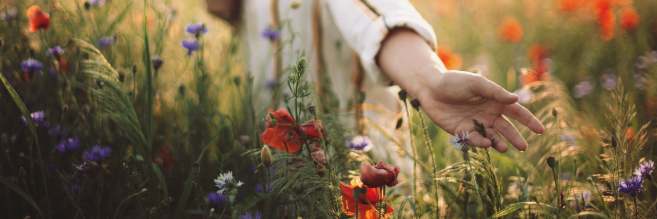 Finding Self-Worth in Life With a Chronic Illness Woman in rustic dress gathering poppy and wildflowers at sunset.