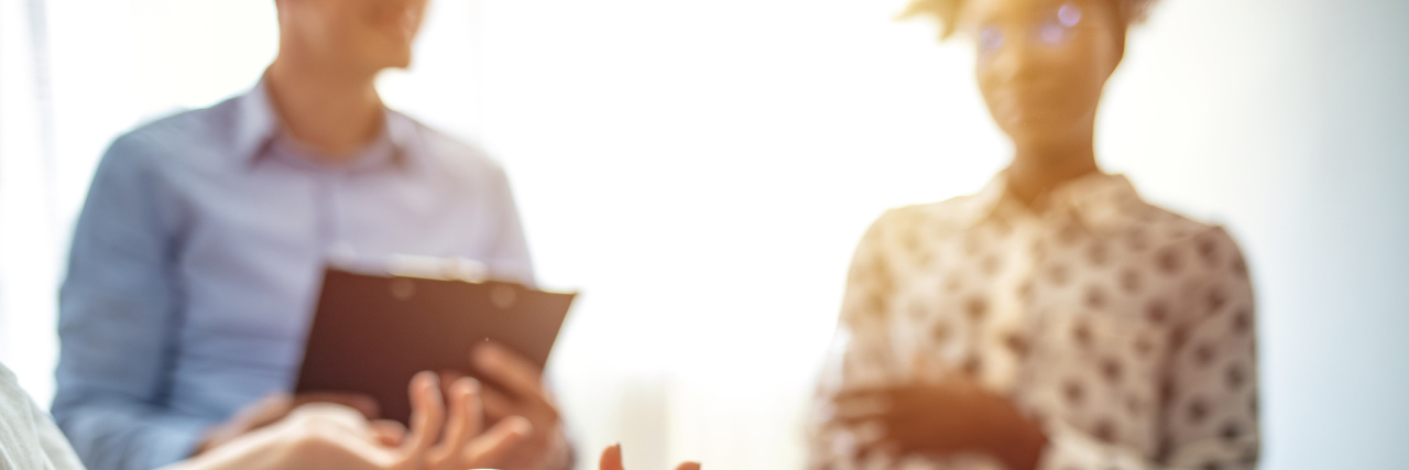 The Best Therapists Understand How to Be Culturally Sensitive A white female therapist's hands explaining something to two of her clients; a white man and a Black woman, both smiling
