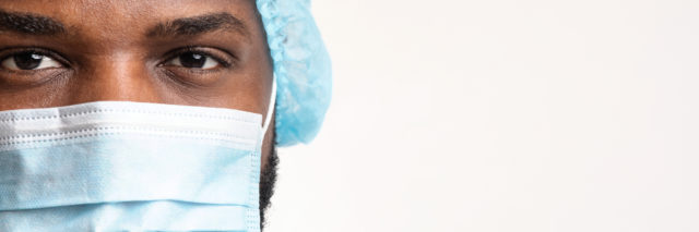 Close up of a Black health care working wearing a cap and surgical face mask