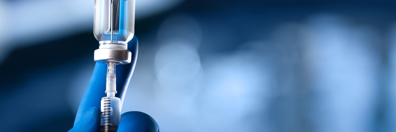 An Autistic Actor's Take on Vaccine Hesitancy Nuse filling vial with vaccine.