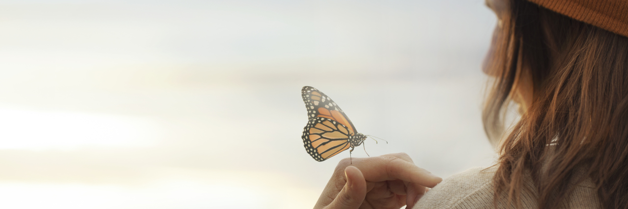 Apologies and Chronic Illness colorful butterfly laying in a woman's hand