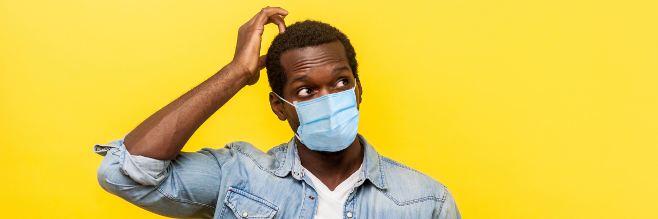 App Helps Calculate the COVID-19 Risk of Activities Outside Your House man with surgical medical mask looking up, scratching head while thinking with confused puzzled face.