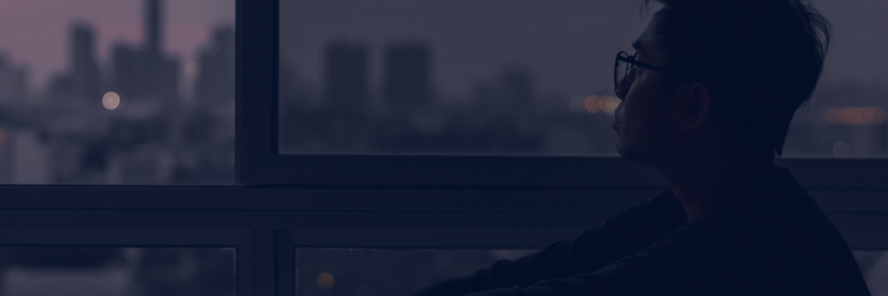 Staying Awake for an EEG When It Could Harm My Mental Health photo of young man sitting beside window at dusk, looking over city