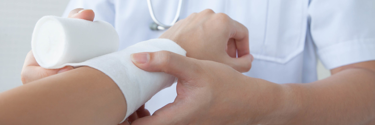 Doctor bandaging woman's arm.