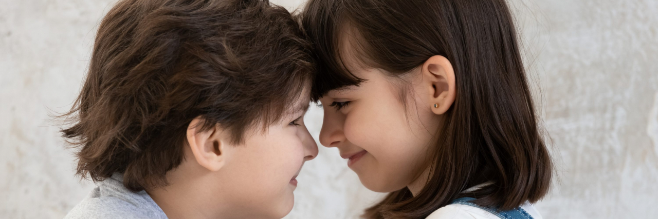 Young brother and sister smiling with their foreheads pressed together