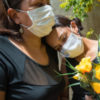 Mother and daughter, both wearing facemasks mourn the loss of COVID-19 patient with yellow roses