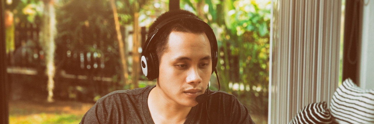 Learning to Use Voice Recognition Software With a Movement Disorder Man on laptop with microphone headset.