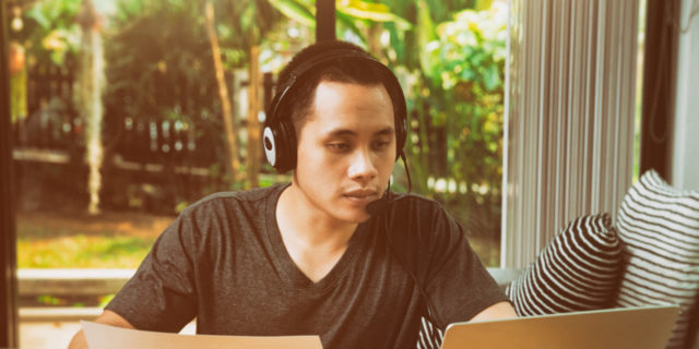 Man on laptop with microphone headset.