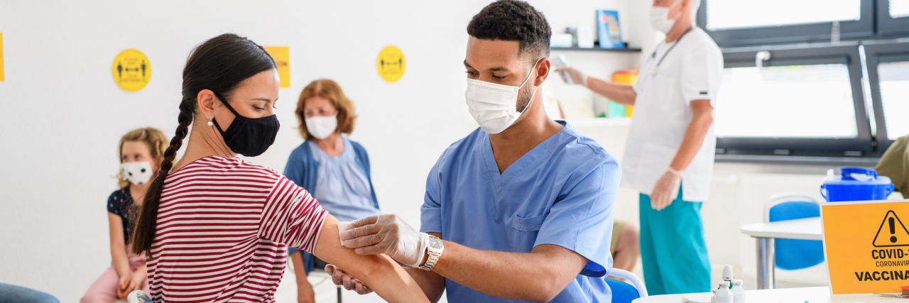 3 Medical Experts Answer Your COVID-19 Vaccine Questions Young woman with face mask getting vaccinated