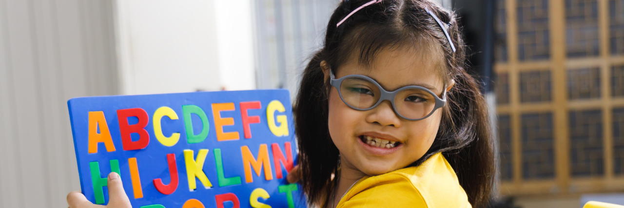 girl with Down syndrome playing with alphabet puzzle toy.