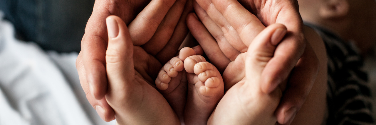 a baby foot being held my hands of parents