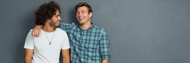 Two friends in casual wear standing and laughing together