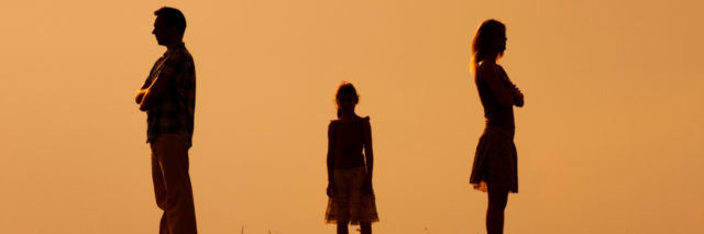 silhouette of a man and woman standing across from each other and a little girl in the middle