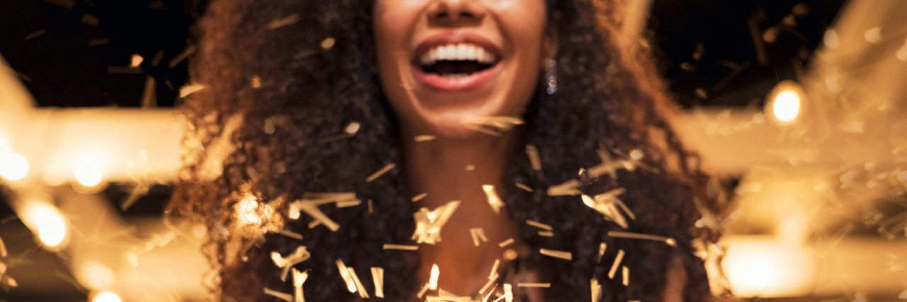 My BPD Recovery Toolkit for Finding Light in the Dark Cheerful Black woman holding single sparkler in hand outdoor.