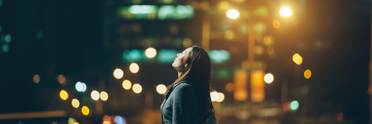 Healing From Trauma: Trigger, Flashback, Response and Growth Woman standing in front of city buildings at night, looking up