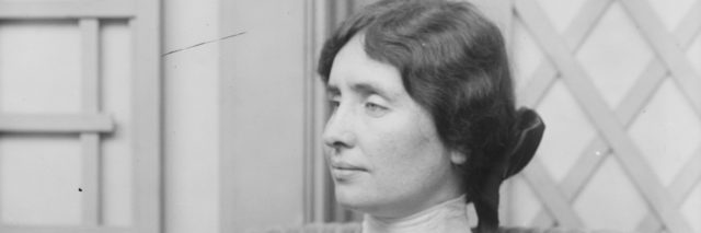 Black and white photo of Helen Keller in middle age with her hair in a bun, shown in profile.