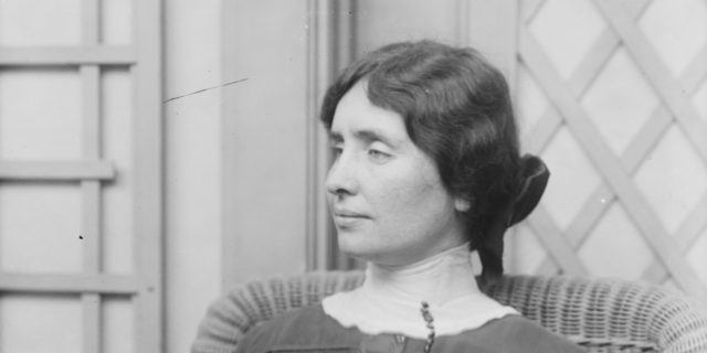 Black and white photo of Helen Keller in middle age with her hair in a bun, shown in profile.