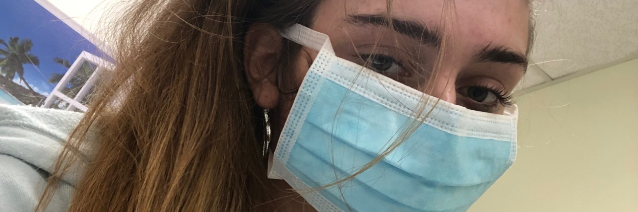 My Psychiatric Hospital Experience During the Coronavirus Pandemic photo of the contributor inside a psychiatric hospital during the coronavirus pandemic, wearing a blue face mask and looking into the camera