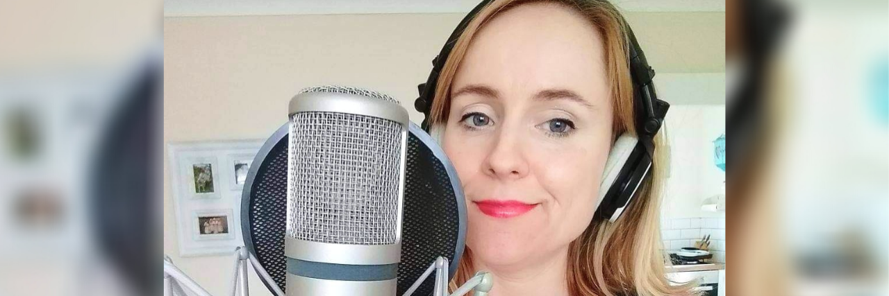 Author Louise Steel with headphones recording in a studio with a soft smile