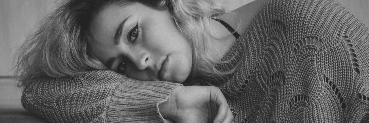 How to Find Motivation When You're Depressed black and white photo of a woman looking tired and unmotivated, looking into camera and resting head on her arm