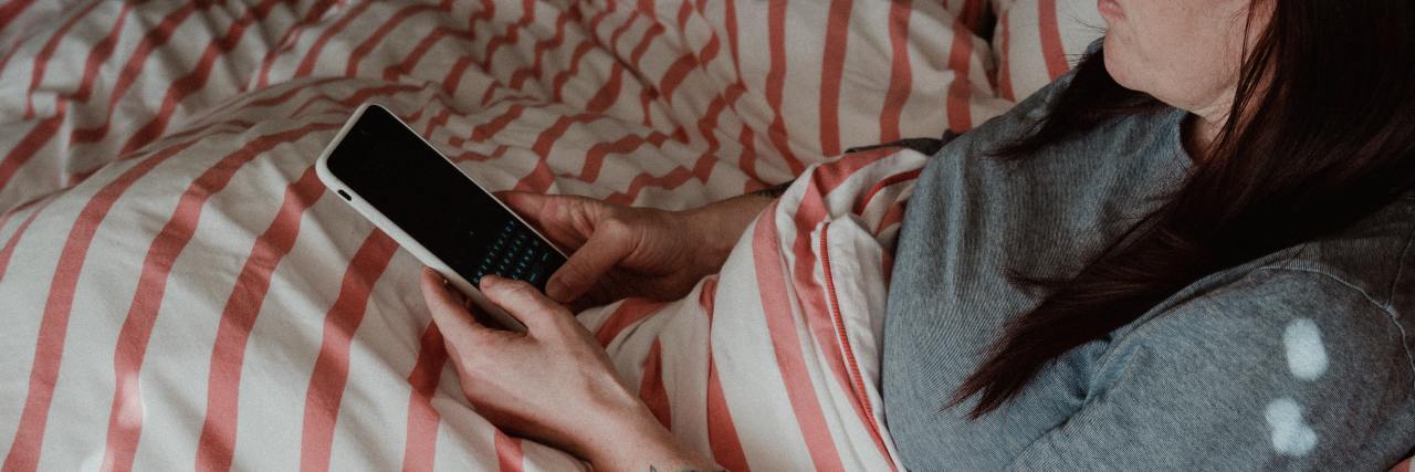 Working on My Mental Health as a Parent a woman sitting in bed looking at her phone