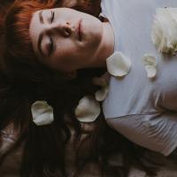 woman sleeping or lying down with her eyes closed, a rose on her chest, photo taken from above