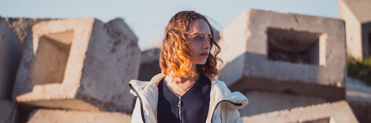Raising Awareness for Median Arcuate Ligament Syndrome (MALS) Photo of woman standing in front of concrete blocks, looking to the side