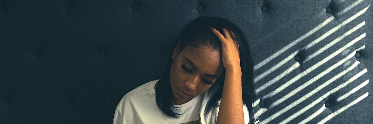 Watching the Insurrection at the Capitol as a Black Trauma Survivor A woman sitting in bed, holding her head in her hands