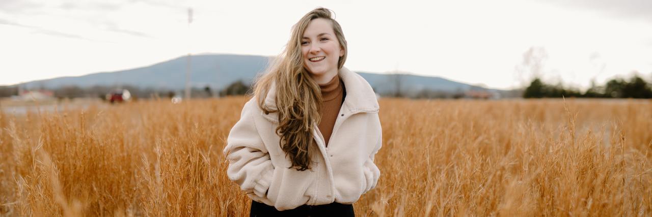 Tips for Staying in Eating Disorder Recovery photo of woman standing in field smiling with her hands in her pockets