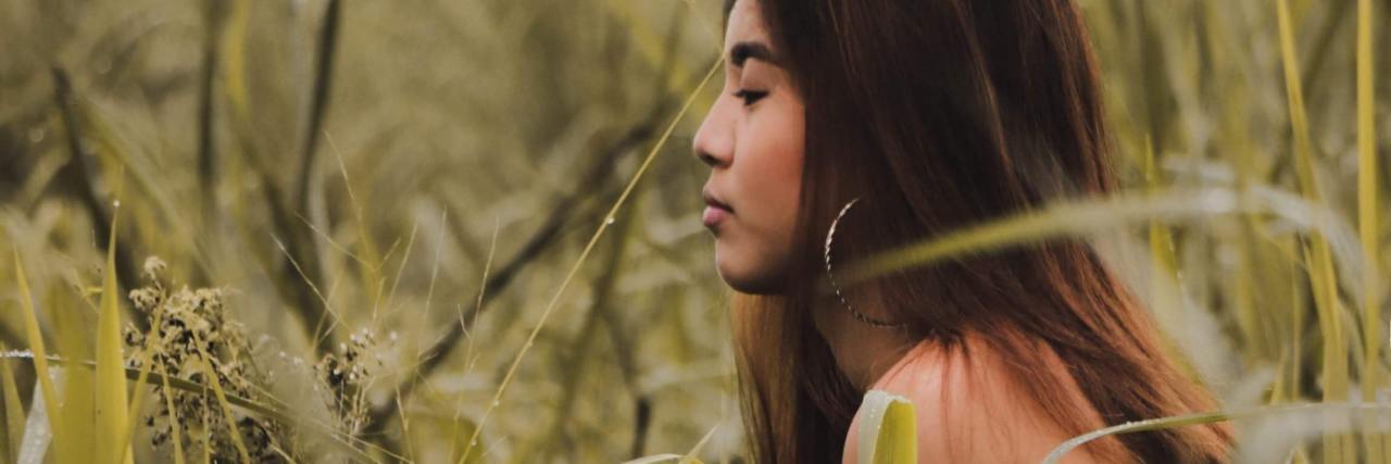 Why Unmet Needs in Relationships Makes the Grass Seem Greener photo of woman lying on her front in a field of long, pale green grass