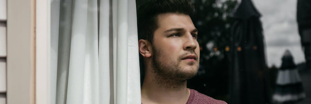 How I Overcome Fear With 5 Questions That Reveal the Truth white man in a red v-neck looking outside the window contemplatively