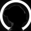 black and white photo of woman in silhouette in front of a circular ring of white light