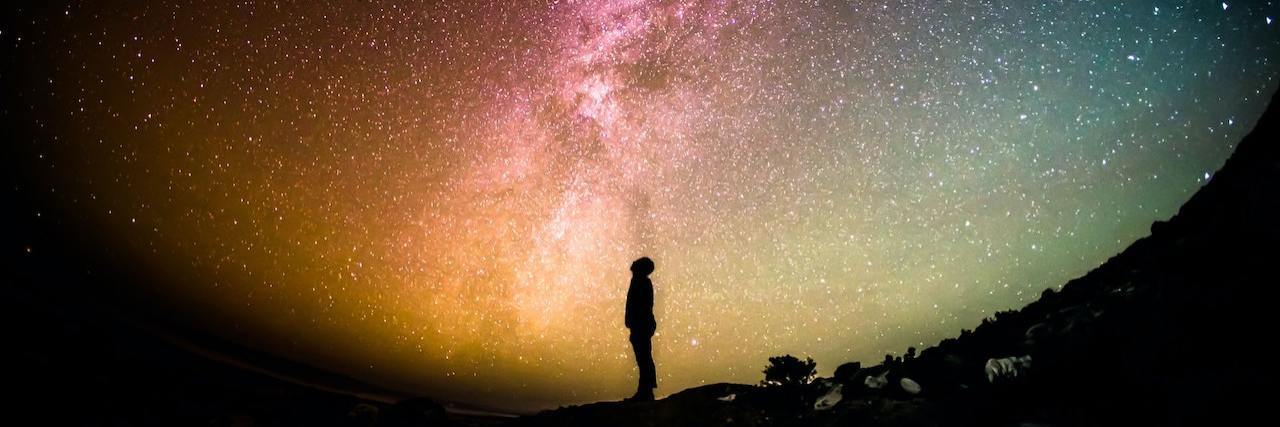 Finding the Positives in the Negative of Depression Silhouette of a person standing in darkness, looking up a bright, colorful sky