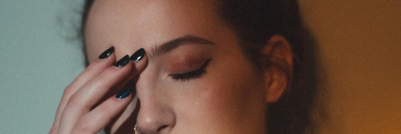 Food Binging and Abusing Medication Won't Help My Emotional Pain photo of young woman in blue and orange lights, pressing fingers to her forehead with her eyes closed as if in pain