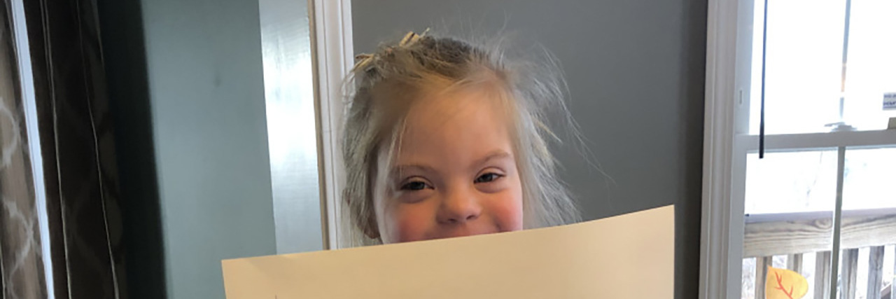 Virtual Kindergarten and My Daughter With Down Syndrome Hannah holding a sign