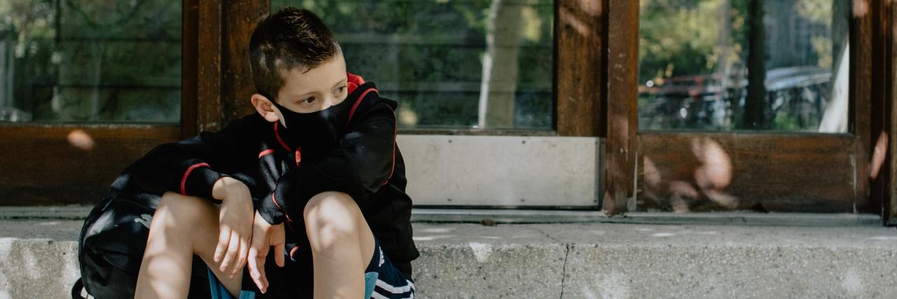 How To Support Your Child in COVID-19 Lockdown in 2021 photo of young boy sitting on steps while wearing a coronavirus covid-19 mask