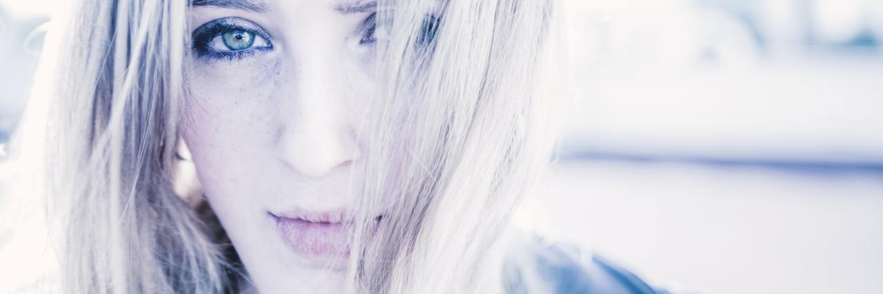 A white woman looking seriously at the camera. She has white blond hair