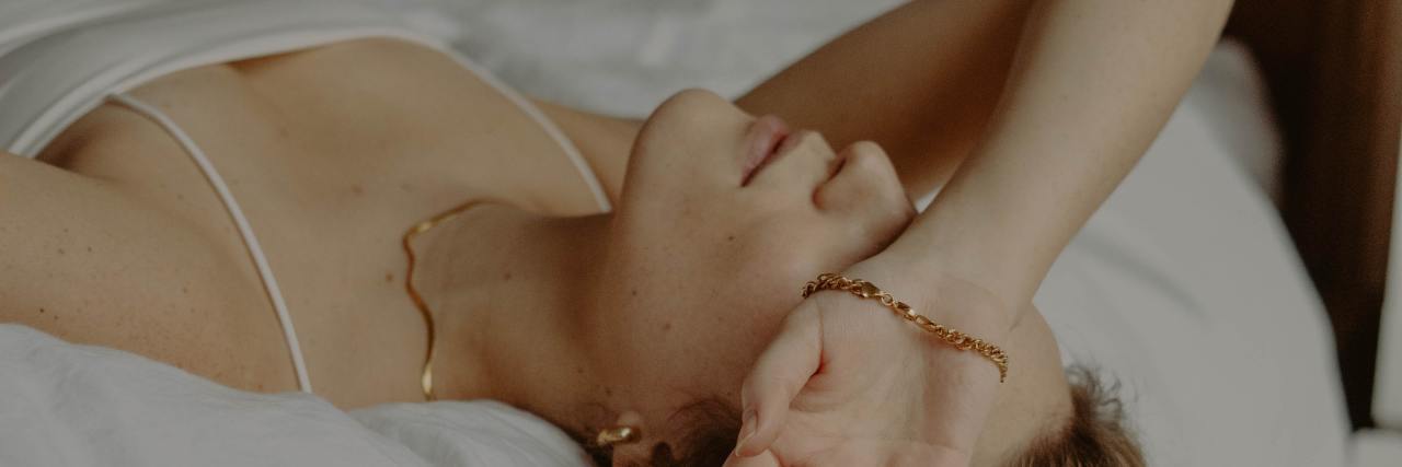 Depression and COVID-19 Make Some Days Feel 'Flat' photo of woman lying on her back on a bed with her arm covering her eyes
