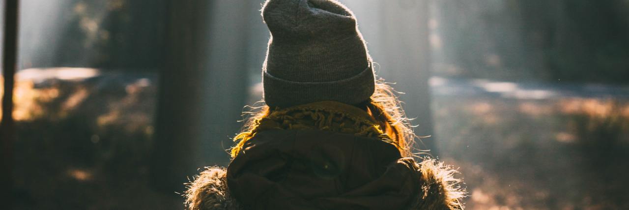 Mental Illness Has Made Me Appreciate Life and Happiness More photo of woman taken from behind, silhouetted by light falling through trees