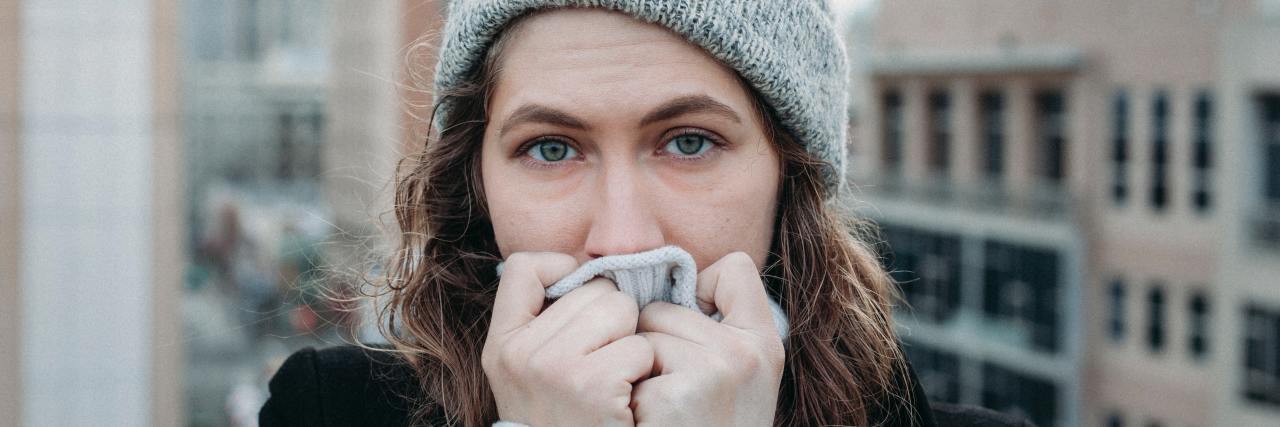 A Trauma Survivor's Advice for Being a Great Therapist photo of woman wearing a hat and covering her mouth while looking into the camera with serious or sad expression