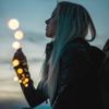 photo of woman at sunset with fairy lights around her wrist and leading to the camera