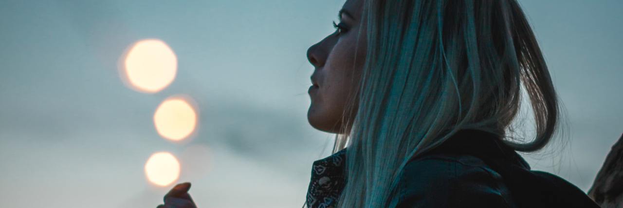 Looking Back on My Childhood Bullying and Hidden Trauma photo of woman at sunset with fairy lights around her wrist and leading to the camera
