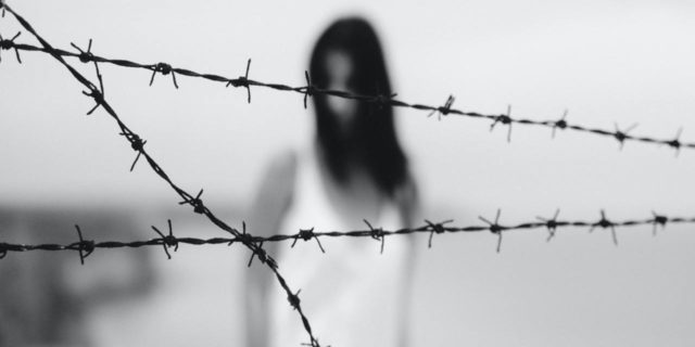 black and white photo of woman blurred behind clear image of barbed wire