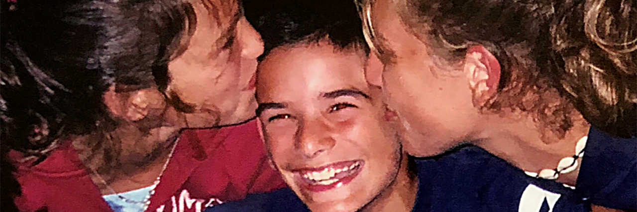 A Letter to My Younger Self, Preparing Me for Epilepsy Kyle as a child with two girls kissing his cheeks.