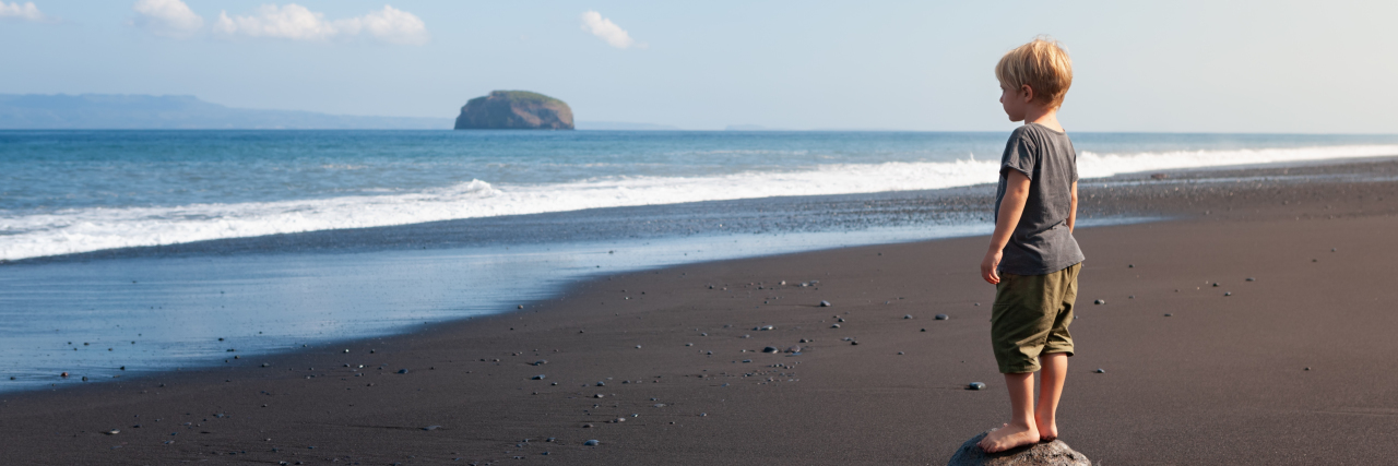 Autism Future Planning: 5 Factors to Consider Child standing on big stone on black sand sea beach