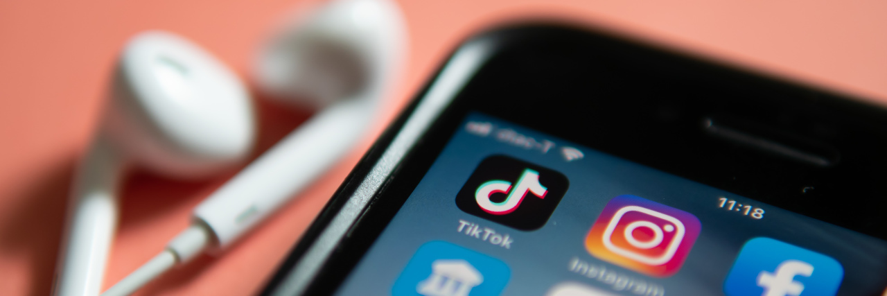 iPhone with TikTok icon and headphones.